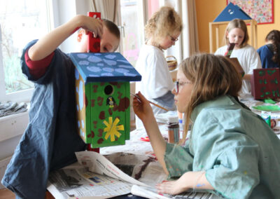 Kinder bemalen ein Vogelhaus
